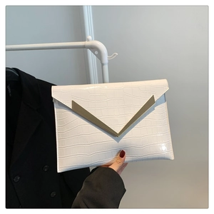 Detail of white crocodile pattern envelope clutch with golden V-shaped metal clasp
