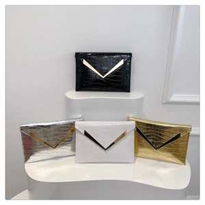 Detail of four crocodile-pattern envelope clutches in black, silver, white, and gold colors