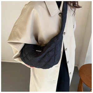 Détail du sac croissant noir matelassé avec lettrage tendance et large bandoulière