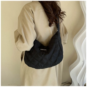 Détail du sac matelassé noir avec étiquette Fashion porté sur un trench-coat beige
