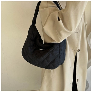 Détail du sac hobo matelassé noir avec étiquette mode et tissu brillant de qualité