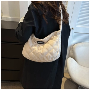 Détail du sac bandoulière matelassé beige en demi-lune avec étiquette Fashion sur modèle
