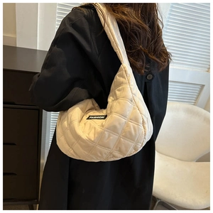 Gros plan d'un sac bandoulière matelassé crème avec motif losange et étiquette Fashion