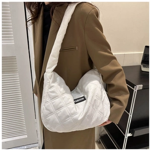 Détail d'un sac cabas blanc matelassé avec étiquette FASHION porté à l'épaule