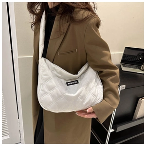 Détail du sac fourre-tout matelassé blanc avec étiquette FASHION noire sur un costume