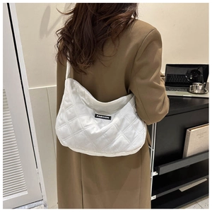 Vue détaillée du sac à bandoulière matelassé blanc en forme de croissant avec étiquette