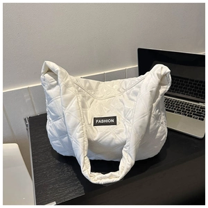 Détail du sac cabas matelassé blanc avec étiquette Fashion sur une table noire