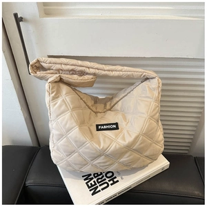 Détail d'un sac à bandoulière matelassé beige avec étiquette fashion sur des livres