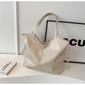 Détail du sac cabas crème avec texture cuir et cordon de serrage sur fond minimaliste