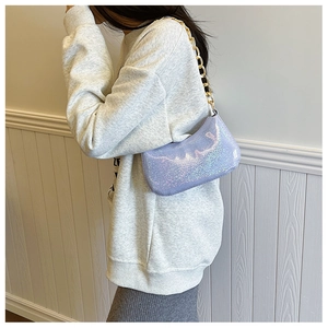 Side view of lavender laser-textured shoulder bag with gold chain strap on model
