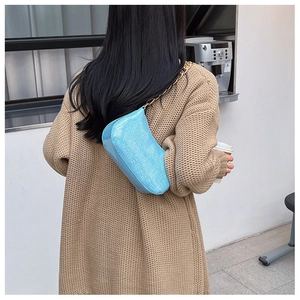 Blue glitter shoulder bag with gold chain shown on a model in a cozy cafe setting