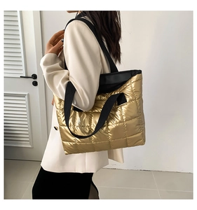 Side view of a person carrying a large quilted gold tote bag with black fabric straps