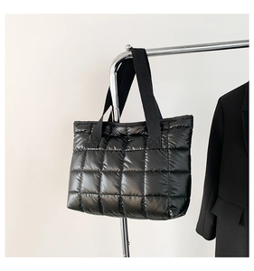Close-up of a black quilted tote bag with padded texture hanging on a metal rack