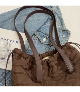 Detail of coffee nylon tote bag with wave quilting and premium long brown leather strap