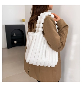 Detail of white faux fur tote bag with striped texture and bubble handles shown on shoulder