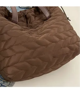 Detail of dark brown quilted tote bag showing leaf-pattern stitching and nylon texture