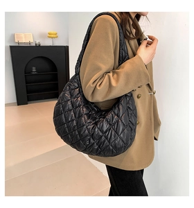 Close-up of a large black quilted tote bag with rhombus pattern on model shoulder