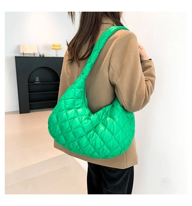 Quilted green puffy hobo bag shown on model wearing a camel blazer in a minimalist setting