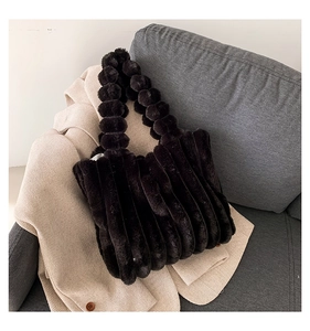Detail of dark brown faux fur tote bag with bubble handle on a beige blazer