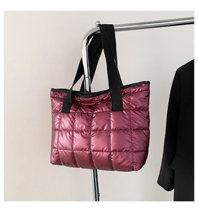 Detail of quilted metallic pink tote bag with black straps and shiny down-style fabric