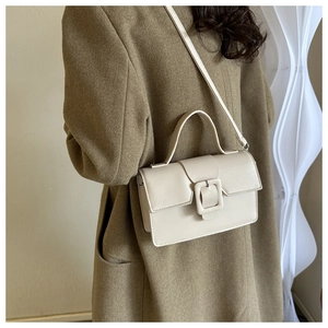 Sac à main en cuir crème chic avec boucle carrée classique porté sur un manteau en laine