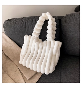 Close-up of white plush tote bag with textured bubble handle on a grey sofa
