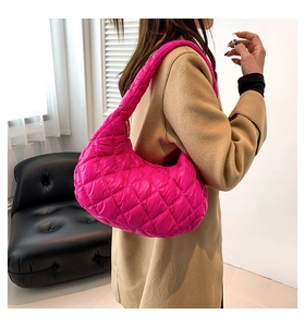 Detailed side view of hot pink quilted nylon tote bag worn with a wool coat