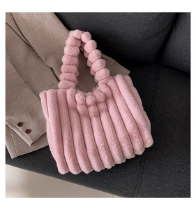 Detail of pink faux fur tote bag with plush ball handles on elegant grey fabric