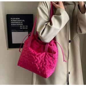 Close-up of a hot pink quilted puffer tote bag with drawstring detail and glossy finish