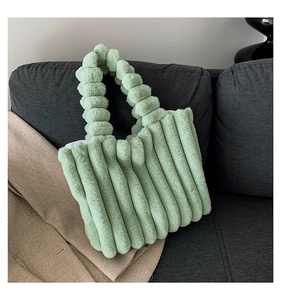 Detail of mint green plush tote bag with a soft cylindrical quilted texture on a sofa