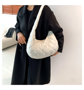 Close-up of a white quilted shoulder bag with diamond stitching on a model side-view