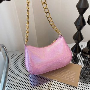 Pink glitter baguette shoulder bag with gold chain strap for women on display