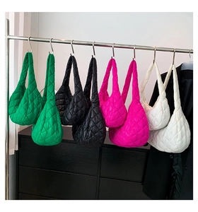 Detailed display of four colored quilted tote bags hanging in an indoor display setting