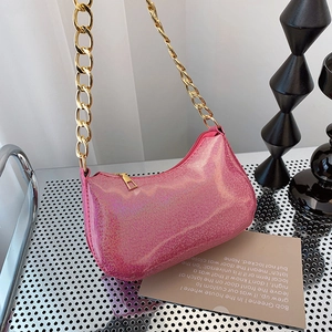 Pink glitter underarm bag with a bold gold chain strap shown on a modern metallic stand
