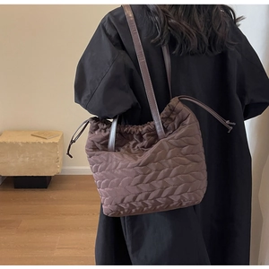 Detailed side view of brown quilted nylon tote bag with drawstring closure and slim straps