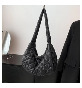 Detail of black quilted puffer tote bag with glossy finish and diamond pattern texture