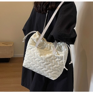 Detail of white quilted nylon drawstring tote bag with elegant wavy stitching textures