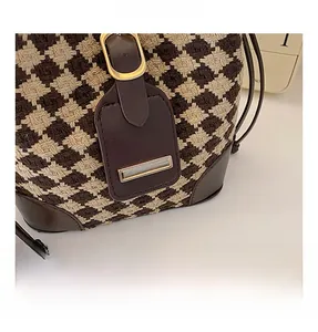 Détail macro du tricot pied-de-poule et des ferrures dorées d'un sac seau chic