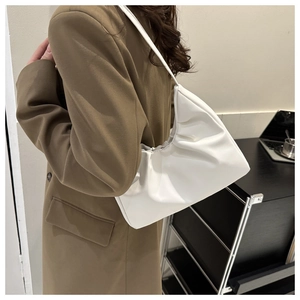 Close-up of a cream pleated cloud bag worn with a brown blazer for a chic autumn look