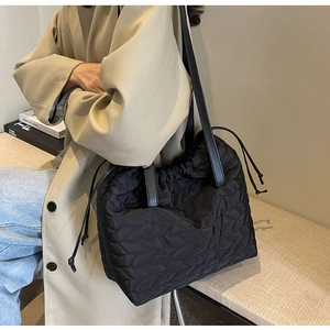 Close-up of black quilted nylon drawstring tote bag with elegant wavy stitching