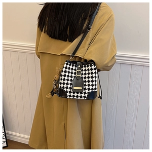 Detail of checkered tweed bucket bag with black leather trim and cute bear charm pendant