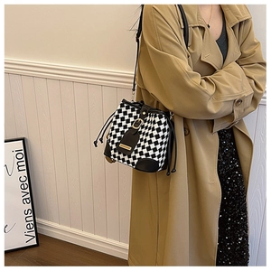 Gros plan d'un sac seau en tricot à damier noir et blanc avec garniture en cuir