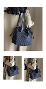 Detail of black quilted nylon tote bag with drawstring closure and leather straps