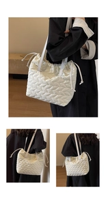 Vertical view of white quilted drawstring shoulder bag with V-pattern stitching detail