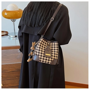 Detail of woven checkerboard bucket bag with leather accents and plush bunny charm