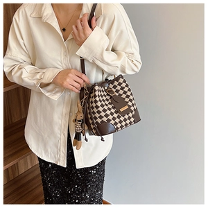 Détail du sac seau à damier avec bordure en cuir et breloque lapin assortie en gros plan