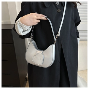 Détail du rabat en forme de cœur et du texte LOVE embossé sur le sac demi-lune argenté