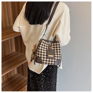 Brown checkered bucket bag with cute rabbit charm worn as a crossbody style