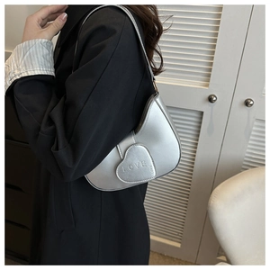 Détail d'un sac argenté avec poche en forme de cœur et embossage LOVE sur le côté