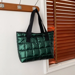 Metallic green quilted puffer tote bag with black canvas straps hanging on a wooden hook